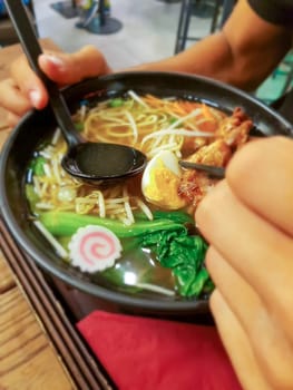 Detail of a typical ramen dish in a Japanese restaurant. Detail of young man's hands.