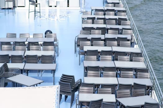 The top view of a noble and well maintained sundeck a passenger ship with tables and chairs...