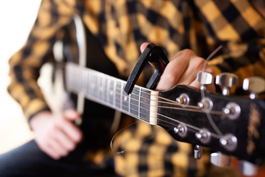 The young man tuning the electric guitar. Closeup