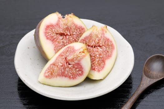 Ripe sweet fig on a plate on black background