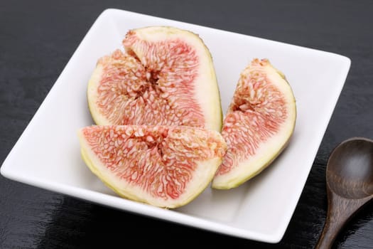 Ripe sweet fig on a plate on black background