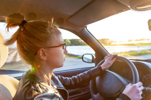 Casual caucasian woman driving a passenger car for a journey in countryside.