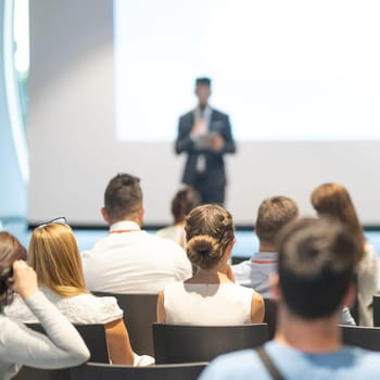 Male speaker giving a talk in conference hall at business event. Audience at the conference hall. Business and Entrepreneurship concept. Focus on unrecognizable people in audience.