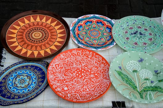 Ceramic plates, hand-painted with a dot pattern, are on the counter at the festive fair