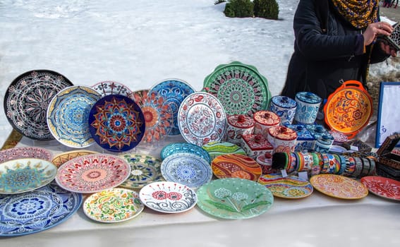Ceramic plates, hand-painted with a dot pattern, are on the counter at the festive fair
