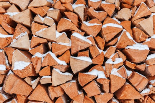 Full-size frontal view of freshly beaten, stacked and snow-covered firewood.