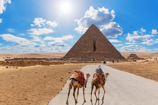 Road to the Pyramid of Menkaure and the bedouin with camels, Giza, Egypt.