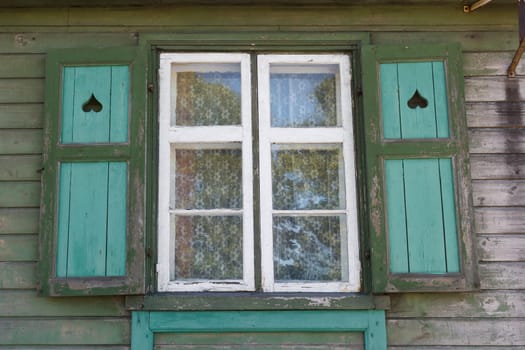 simple window with shutters on a green wooden wall