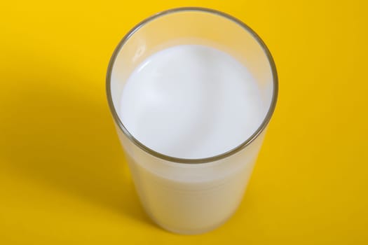 Glass of fresh milk on yellow background