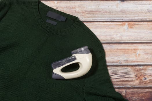 wool sweater with electric lint remover on wooden background