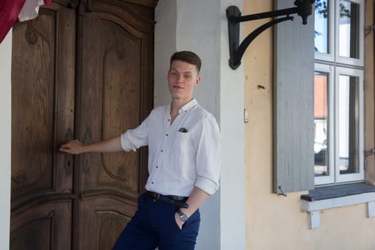 The well-dressed man stands outside by the door