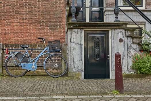AMSTERDAM, NETHERLANDS - SEPTEMBER 21, 2017: Bicycle as popular way of transport in Amsterdam Netherlands parked and locked in front of traditional house in Holland.