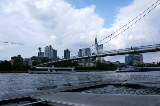 Frankfurt, Germany - August 03, 2019: The skyline and river landscape at the river Main with passenger ships on August 03, 2019 in Frankfurt.