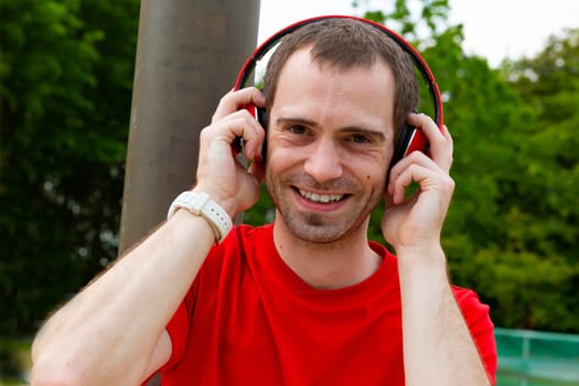 Young joyful Sportsman with red headphones in nature