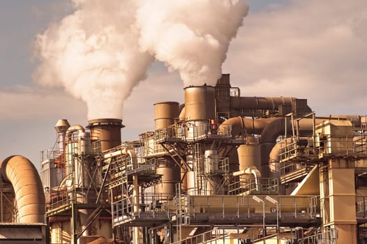 Smoking chimneys pipes and silos of a chemical complex of a factory.