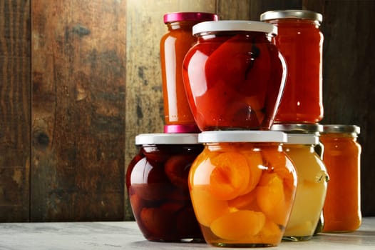 Jars with pickled vegetables, fruity compotes and jams in cellar. Preserved food