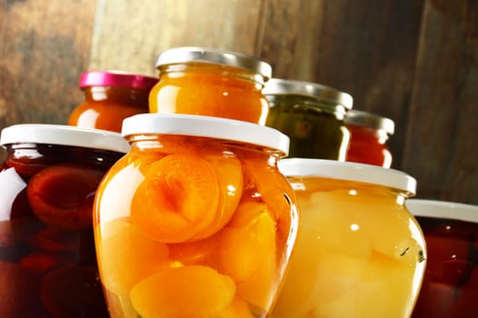 Jars with pickled vegetables, fruity compotes and jams in cellar. Preserved food