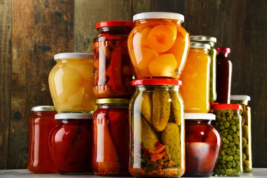 Jars with pickled vegetables, fruity compotes and jams in cellar. Preserved food