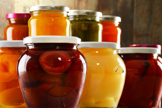 Jars with pickled vegetables, fruity compotes and jams in cellar. Preserved food