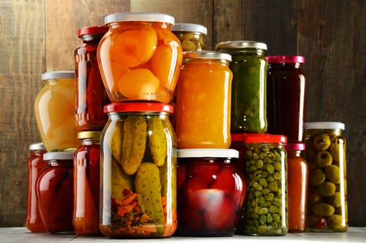 Jars with pickled vegetables, fruity compotes and jams in cellar. Preserved food