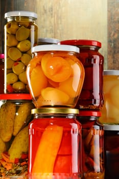 Jars with pickled vegetables, fruity compotes and jams in cellar. Preserved food