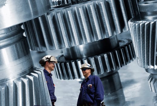 two engineers, workers with large cogwheels machinery