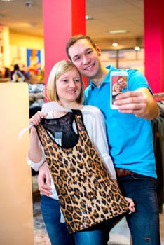young couple in the clothes shop looking for a new dress and take a selfie