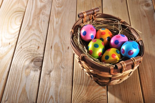 Easter nest with colored painted chicken eggs on old weathered wooden boards