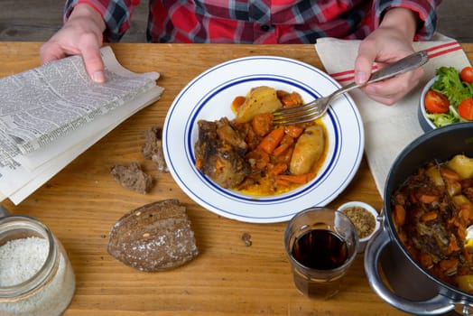 a man eat beef carrot and reading a newspaper