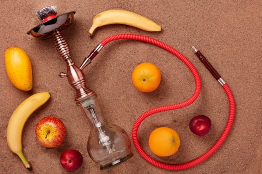 Turkish hookah (shisha) and fruit on a sand background.