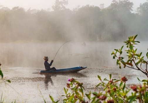 BANGKOK, THAILAND - 05 March 2014 :Fisheman sit on the boat and are looking for fish in the river in the midst of the fog in the countryside
