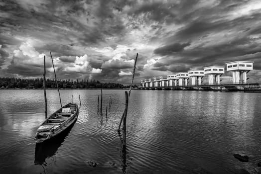 Fishing boat and water barrier and river with cloud sky storm in rain season, Black and white and monochrome style