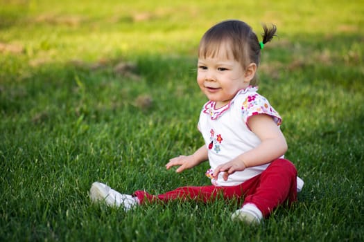 The cute little girl is playing outdoors on the grass.