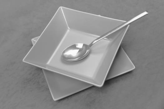 The gray square shaped plate with spoon is served on gray table, modern design crockery.