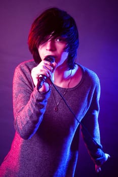 The young guy in emo style is singing in microphone.
