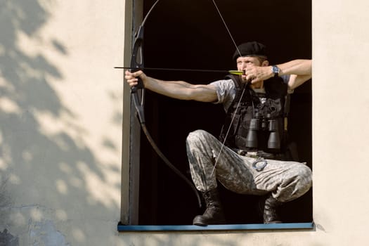 The archer is aiming with bow and arrow in the window, archery concept.
