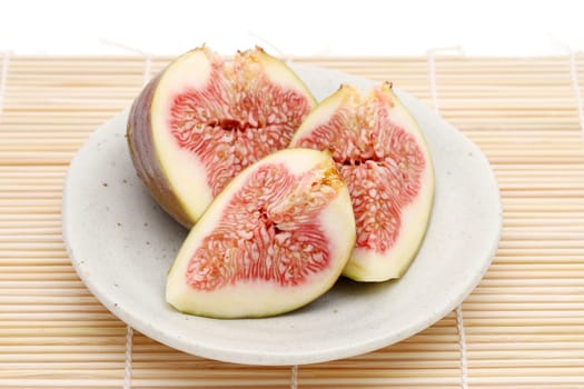 Ripe sweet fig on a plate on bamboo background