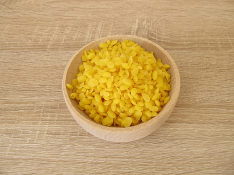 Pure beeswax pastilles in a wooden bowl for natural cosmetics, candles or beeswraps