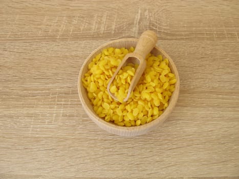 Pure beeswax pastilles in a wooden bowl for natural cosmetics, candles or beeswraps