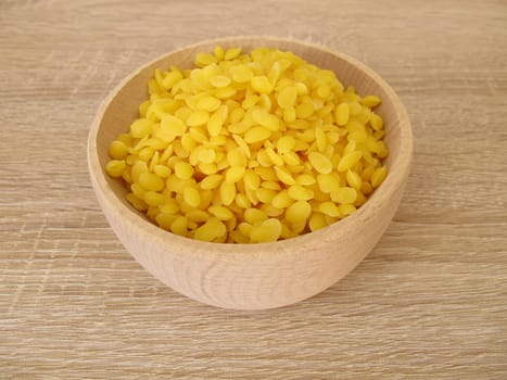 Pure beeswax pastilles in a wooden bowl for natural cosmetics, candles or beeswraps