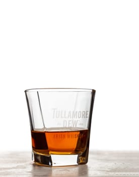 CHISINAU, MOLDOVA - August 20, 2019: Tullamore Dew whiskey in a glass with a company logo. Tullamore Dew is blended Irish whiskey produced by William Grant and Sons since 1829.
