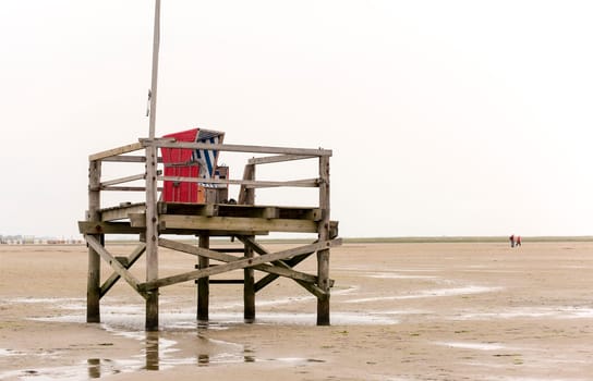 Bathing platform made of wood with beach chair in the Wadden Sea on the German North Sea coast at low tide