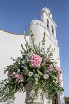 Bridal flowers bouquet close to whitewashed church. Mediterranean wedding decoration concept