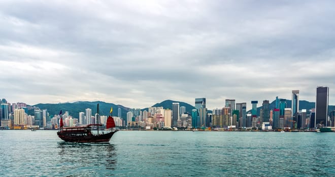 Chinese traditional junk boat in front of Hong Kong island city skyline with high skyscrapers, panorama, Cina