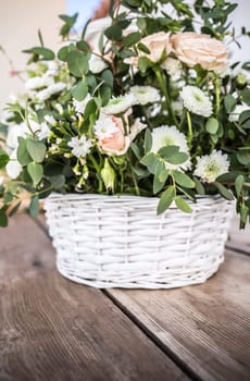 Bridal bouquet composed with wild flowers on basket over wooden table. Selective focus