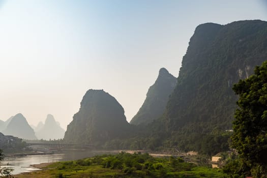 Misty sunrise in the mountains of Asia, a village on the banks of the river, Yangshuo China