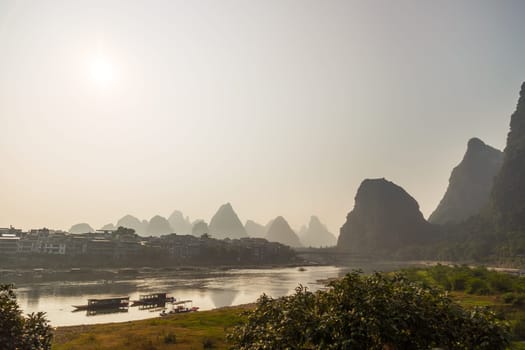 Misty sunrise in the mountains of Asia, a village on the banks of the river, Yangshuo China
