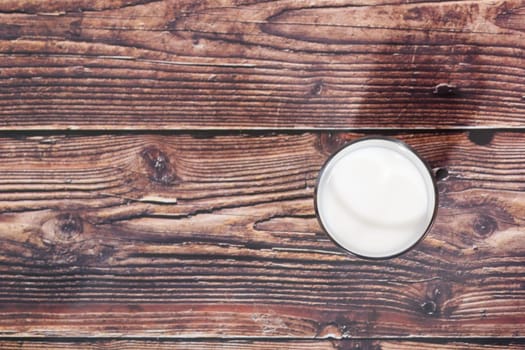 glass of milk on wooden background from above