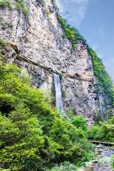 High waterfall falling down from narrow cave in Zhangjiajie in Grand Canyon. Wulingyuan, Hunan, China