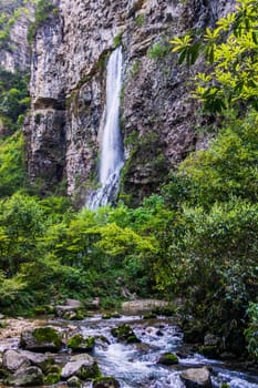 High waterfall falling down from narrow cave in Zhangjiajie in Grand Canyon. Wulingyuan, Hunan, China